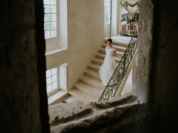 Bride coming down stone staircase to wedding in French Chateau