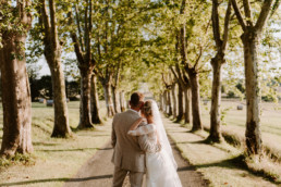 Bride and groom looking down avenue of trees at the Grand Gascon Estate rustic wedding venue in the Gers SW France