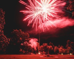 Red firework exploding over trees at French chateau