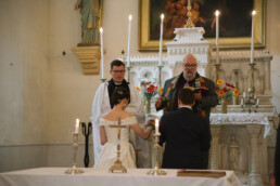 bride_and_groom_kneeling_in_front_of_priest_at_altar_at_wedding_in_France