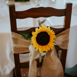 Sunflower tied with hessian ribbon to back of wooden dining chair