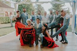 Groom and groomsmen posing with can can dancers in red dresses