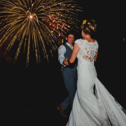 Bride and groom dancing under the light of a big firework exploding
